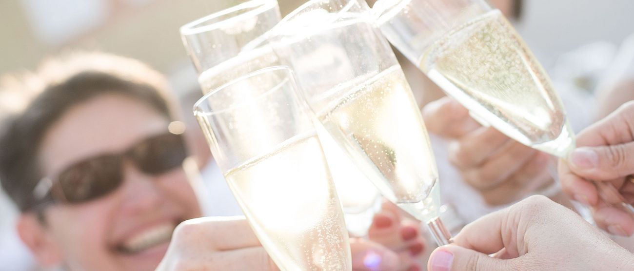 Mehrere Menschen stoßen gemeinsam mit Sekt an.