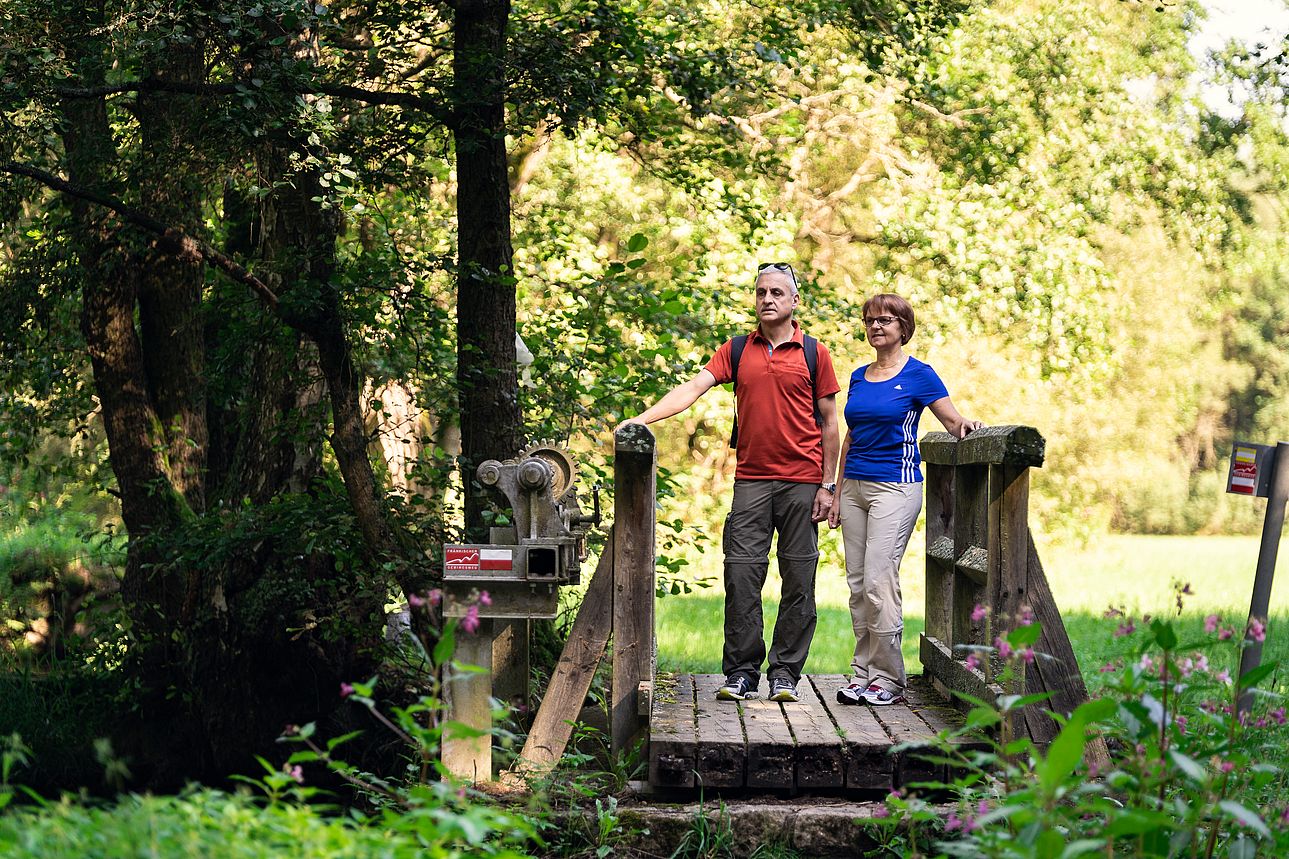 Zwei Wanderer auf einer Brücke über der Wondreb.