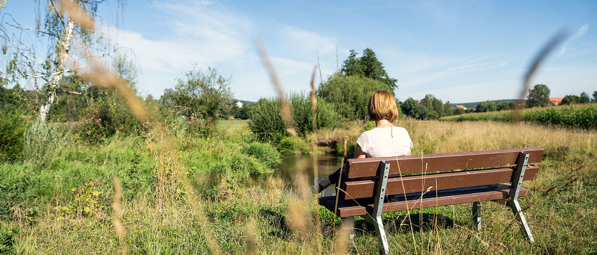 Eine Frau sitzt auf einer Bank mit Blick auf Waldsassen.