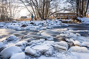 Verschneites und vereistes Wondreb-Wehr bei Waldsassen mit schneebedeckten Steinen und Brücke